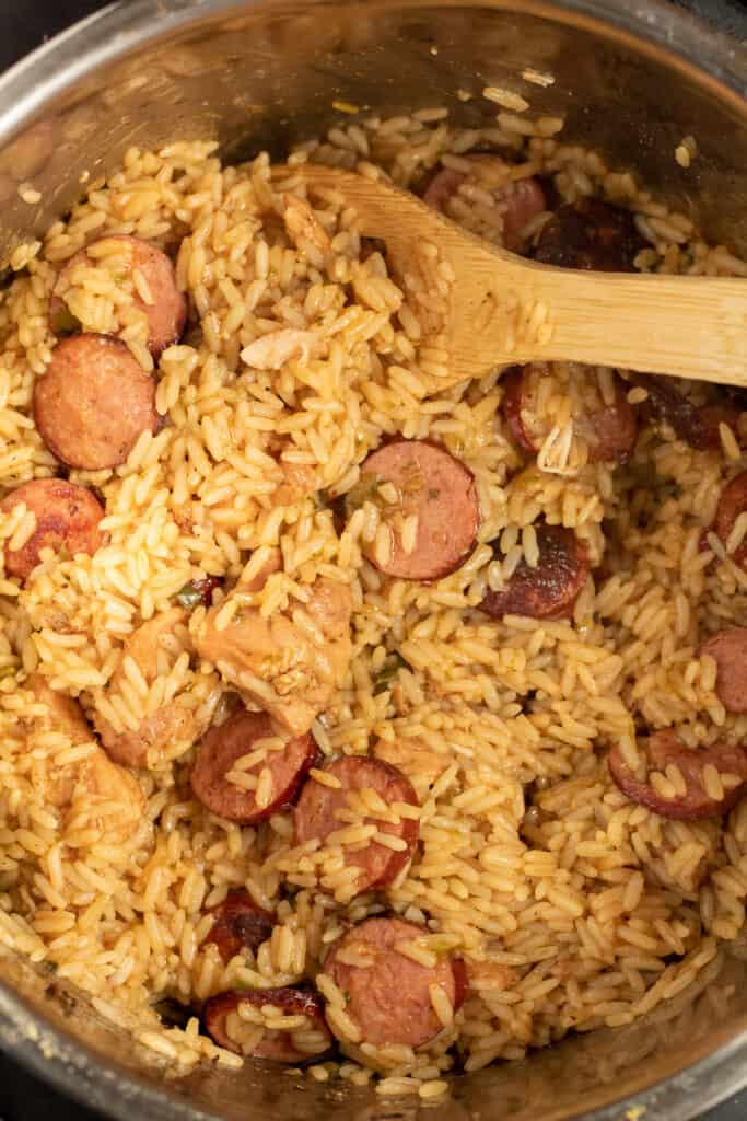 Overhead photo of jambalaya being stirred with a wooden spoon.